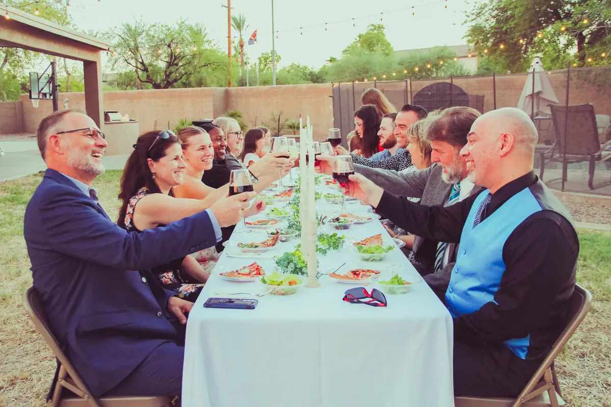 Guests in suits raising a toast at a long-table dinner catered by Local Hive