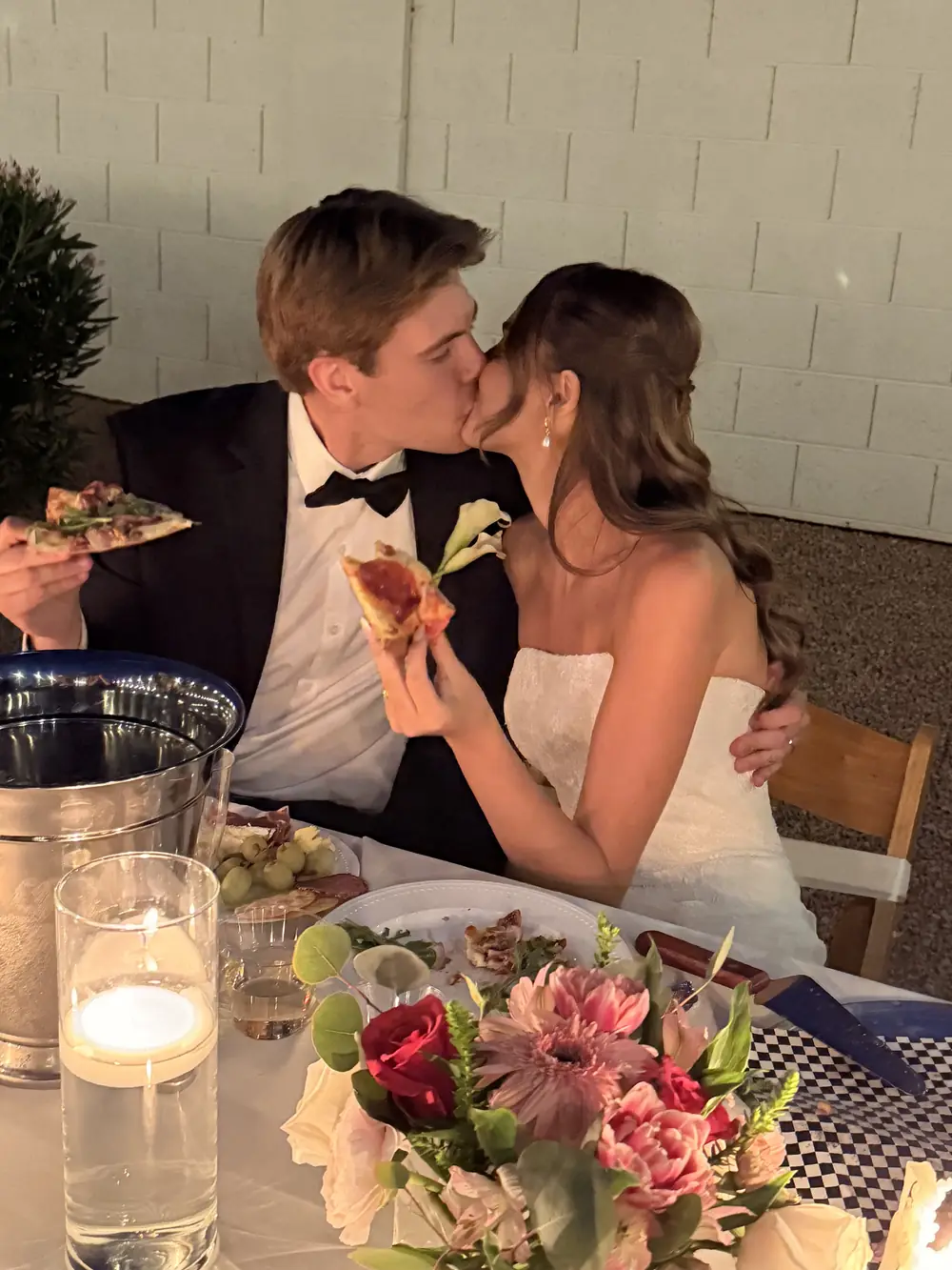 Bride and groom sharing a kiss and a slice of pizza at their reception