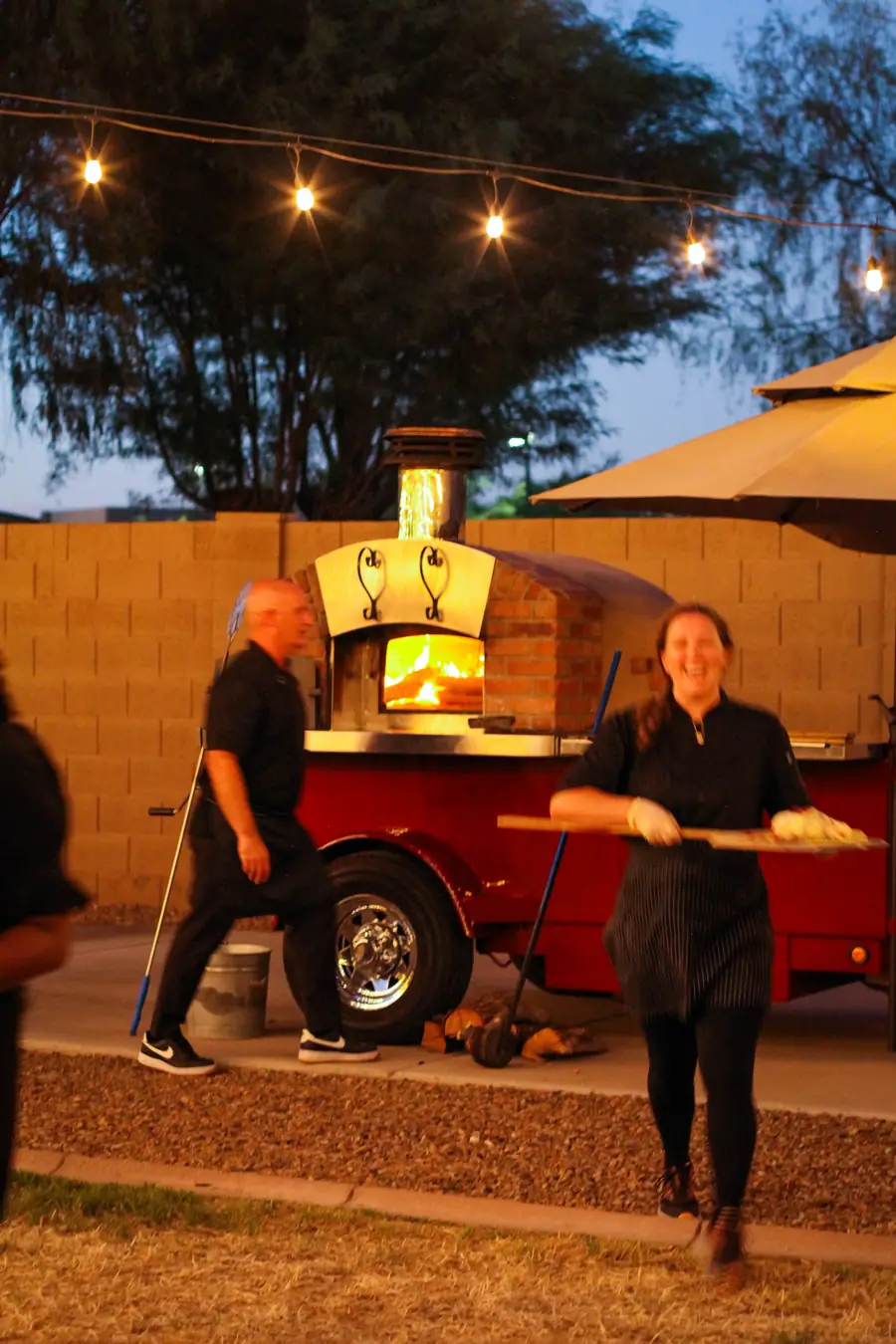 Local Hive team serving at dusk beside the glowing oven