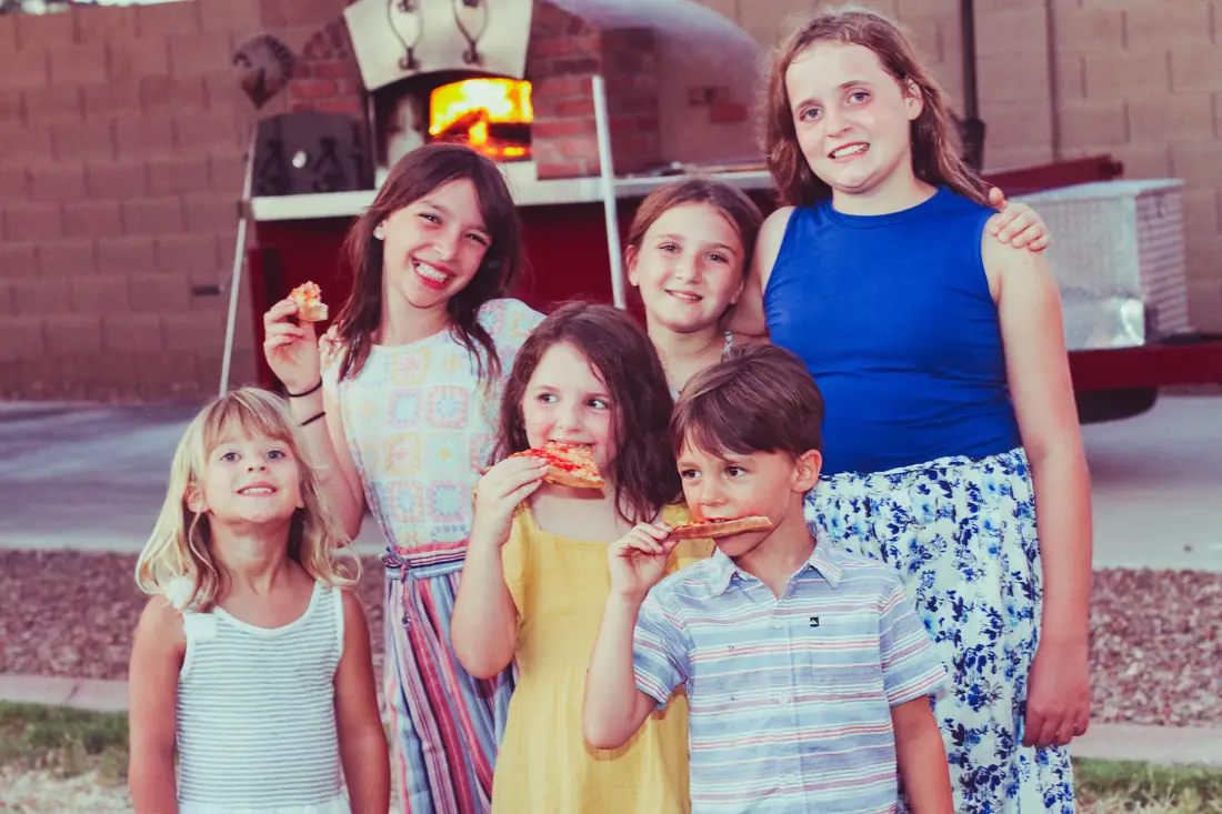 Kids enjoying pizza in front of the wood-fired oven