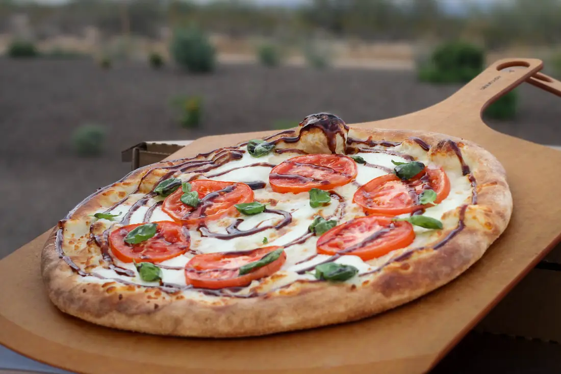 Fresh margherita-style pizza on a wooden peel