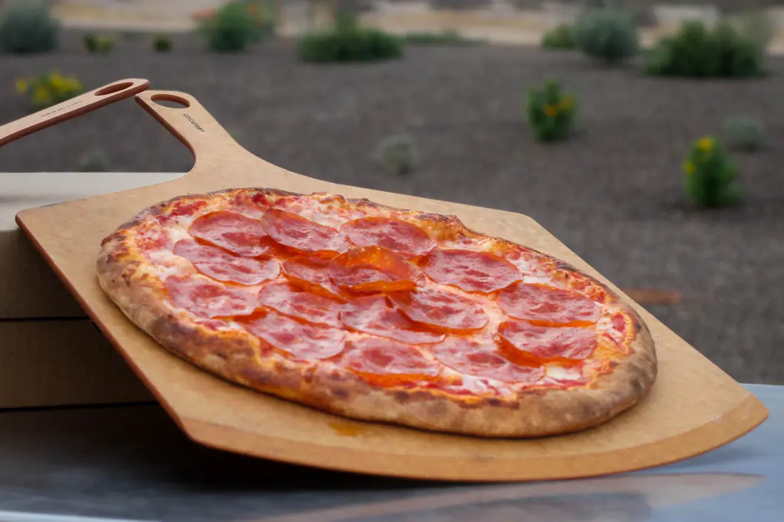 Fresh pepperoni pizza on a wooden peel