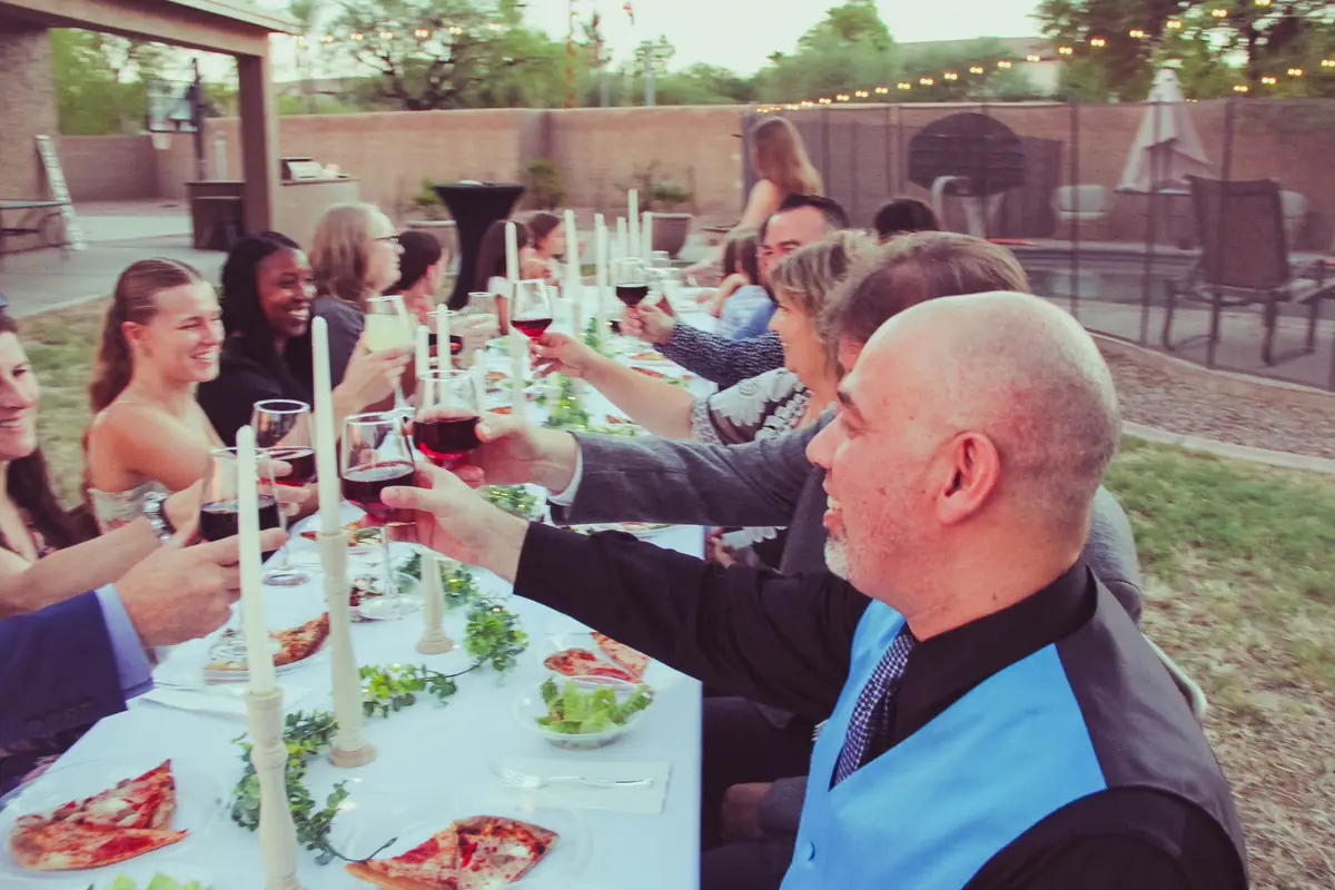 Guests in suits toasting at a long-table dinner catered by Local Hive
