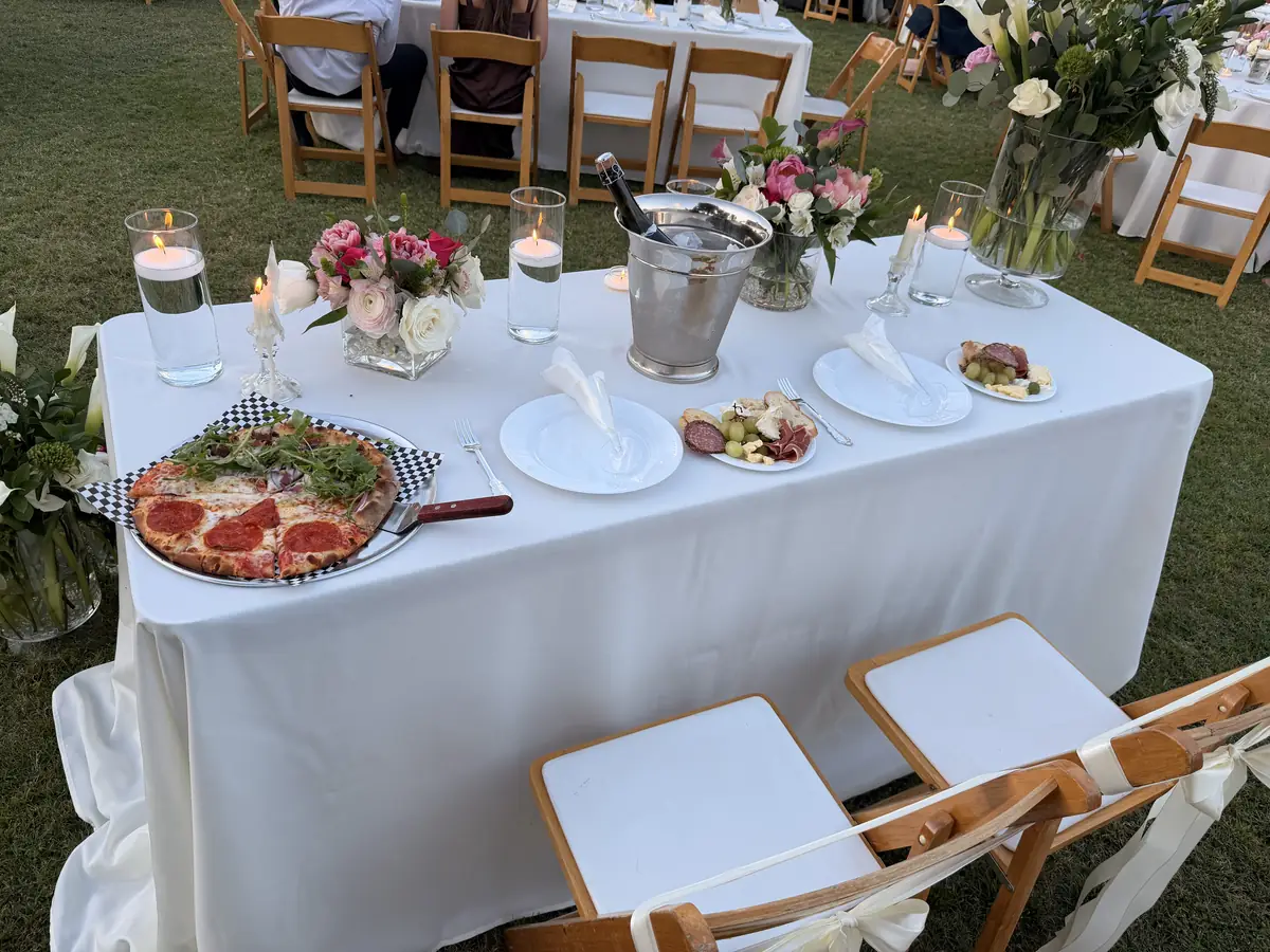 Wedding reception table set with wood-fired pizza and flowers